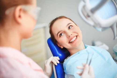 Young female sitting in dentist office and looking at her doctor with soapnotesAI copilot